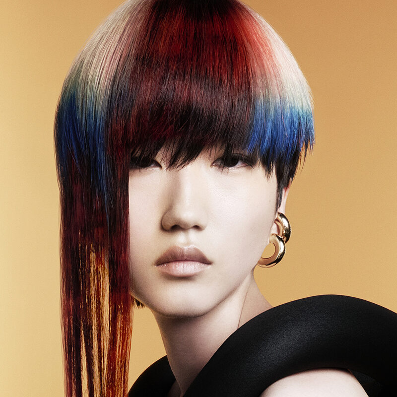 Corte asimétrico con tonos rojo, azul y blanco en acabado espejo, envuelto en escultura textil negra