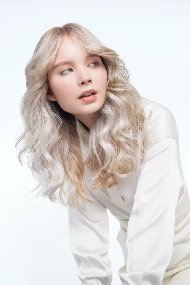 Retrato de mujer con ondas naturales y blusa blanca transparente