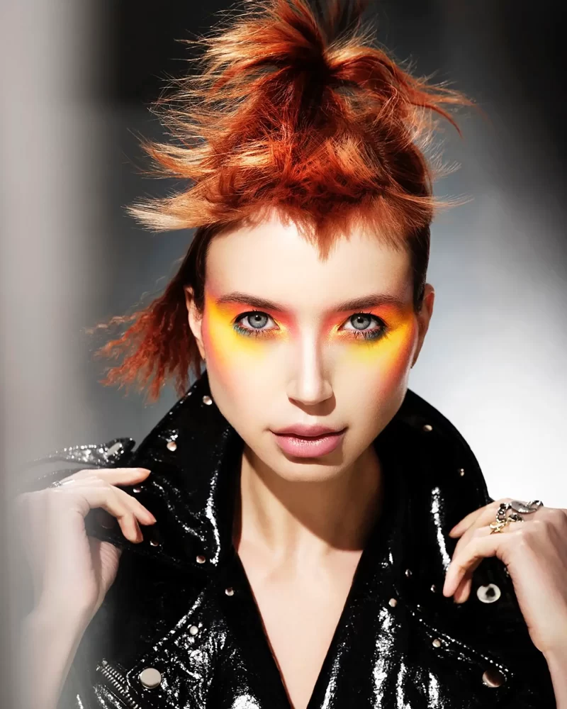 Estilo punk con cabello en tonos cobrizos intensos y maquillaje naranja vibrante, colección Freedom por Kerry Mather.