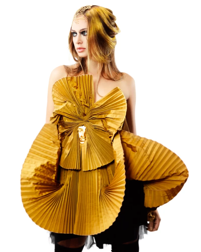 Modelo con cabello dorado suelto, tocado en la frente y corset negro con escultura dorada de león.