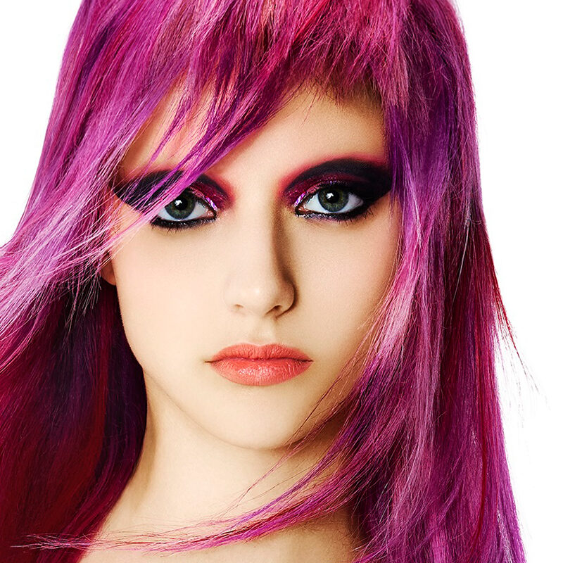 Modelo con cabello largo fucsia eléctrico y fleco texturizado, look editorial de alto impacto de la colección Skittles de George Alderete.
