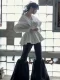 Modelo de perfil con peinado efecto húmedo, blusa blanca oversize y fondo de cristal.