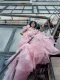 Modelo con vestido rosa en tul y cabello azul, capturada desde una escalera exterior industrial.
