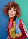 Modelo con rizos en tonos naranjas y rojos, usando chaqueta de estampado animal print multicolor. Colección Metaverso de Alexander Kiryliuk.