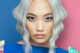 Modelo con cabello rubio platinado en ondas marcadas, peinado con raya al centro. Vestido con mangas coloridas. Colección Metaverso de Alexander Kiryliuk.