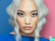 Modelo con cabello rubio platinado en ondas marcadas, peinado con raya al centro. Vestido con mangas coloridas. Colección Metaverso de Alexander Kiryliuk.