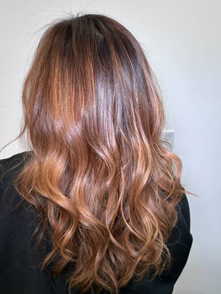 Cabello femenino con coloración desvanecida en tonos cálidos y ondas naturales realizado con Igora Zero Amm