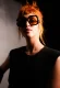 Recogido messy cobrizo con fleco mini y gafas naranjas oversize; textura viva.
