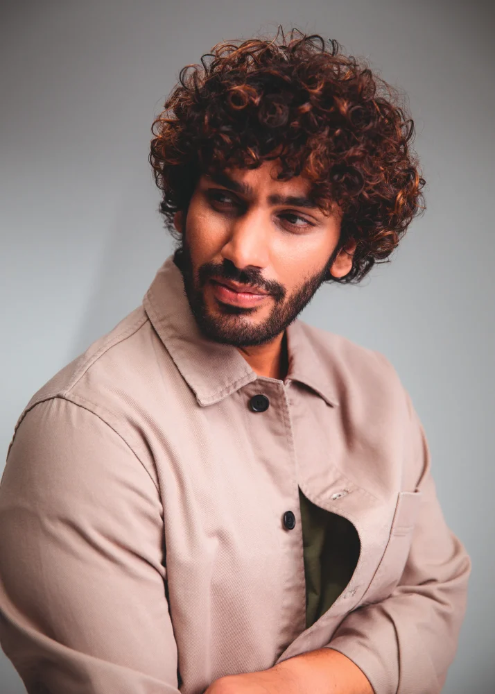 Modelo masculino con cabello rizado definido y textura natural trabajado con técnicas profesionales de Schwarzkopf Professional.