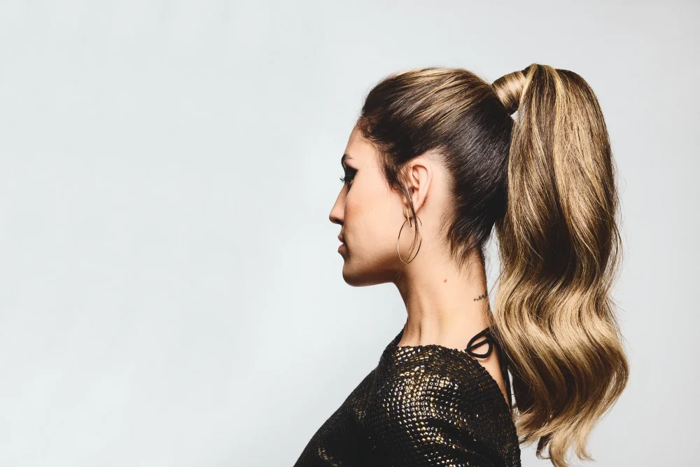 Perfil lateral de modelo femenina con coleta alta pulida y acabado profesional de Javier Díaz para Schwarzkopf Professional.